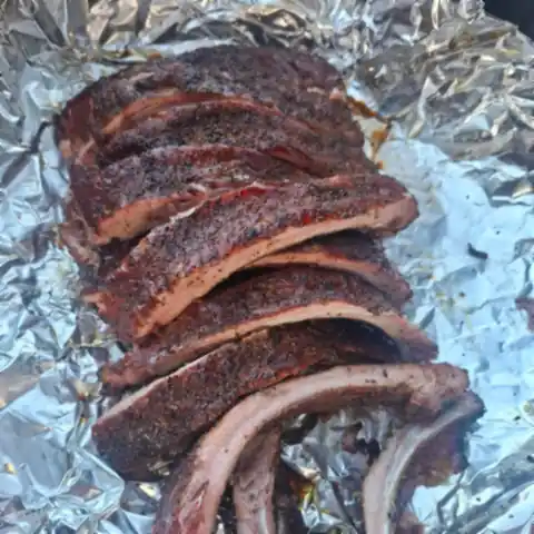 Smoked pork spare ribs with a peppery rub, sliced on foil